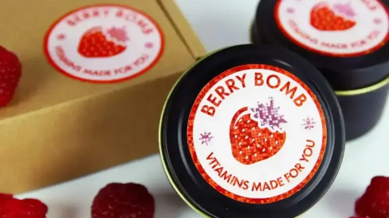 Round custom vinyl labels on black tins beside kraft packaging